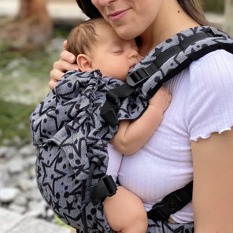 Bambino che riposa appoggiato al genitore nel marsupio