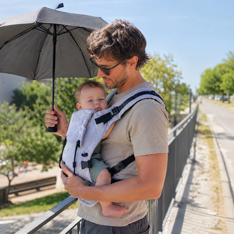 Genitore con bambino in marsupio ergonomico in estate